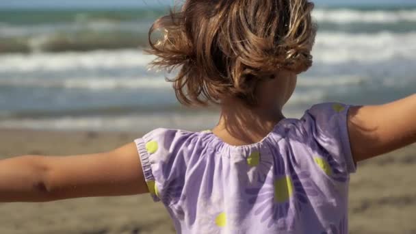 Käsite vapaus, pieni tyttö avosylin edessä valtameren isoja aaltoja, hidastettuna lähikuva - Materiaali, video