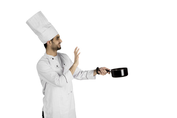 Young chef cooking with a pan on studio - Foto, imagen