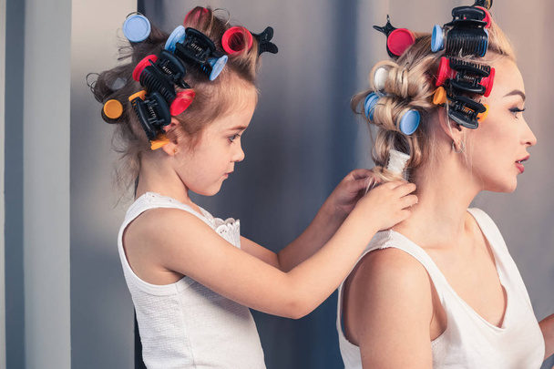 Beautiful young mother and her daughter with hair curlers - Foto, immagini