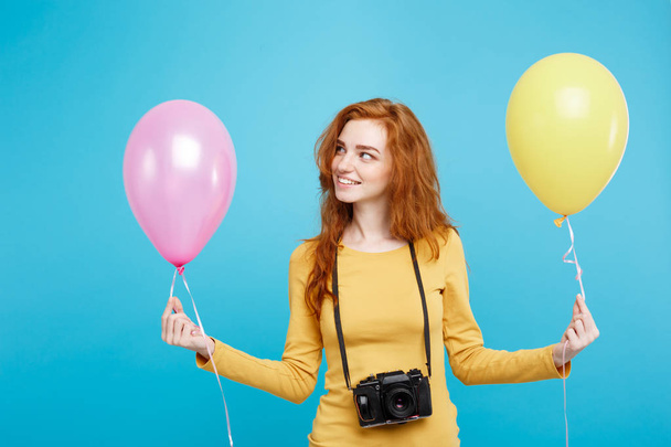 Lifestyle und Party-Konzept - Nahaufnahme Porträt junge schöne attraktive Ingwer rote Haare Mädchen mit bunten Luftballon und Vintage-Kamera. blauer Pastellhintergrund. Kopierraum. - Foto, Bild