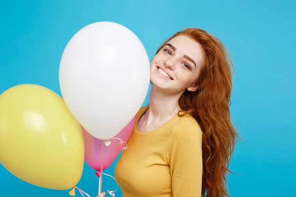 Primer plano Retrato feliz joven hermosa chica pelirroja atractiva sonriendo con globo de fiesta colorido. Fondo azul pastel
. - Foto, imagen
