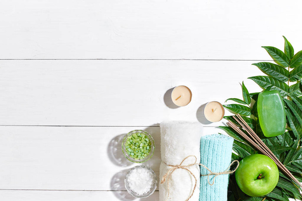 Wellness-Produkte. Badesalze, Seife, Kerzen und Handtuch. flache Lage auf weißem Holzgrund, Draufsicht. - Foto, Bild
