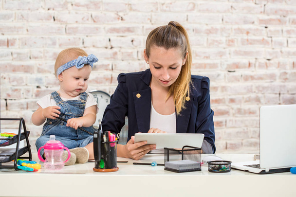 Maman et femme d'affaires travaillant avec un ordinateur portable à la maison et jouant avec son bébé fille
. - Photo, image