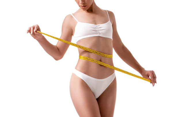 Mulher medindo seu corpo magro isolado no fundo branco
 - Foto, Imagem