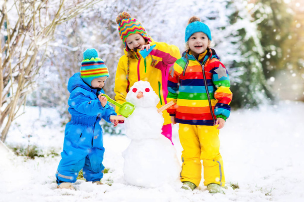 Crianças a construir boneco de neve. Crianças na neve. Diversão de inverno
. - Foto, Imagem