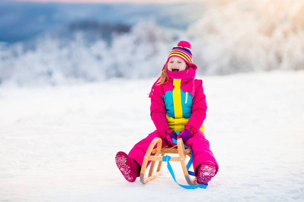Dziecko grając w śniegu na sanie w winter park - Zdjęcie, obraz