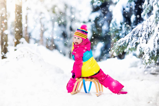 Kind spelen in de sneeuw op de slee in winter park - Foto, afbeelding