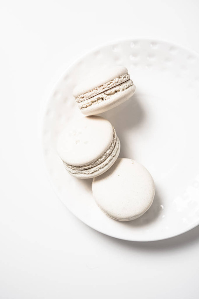 Three beige white macaroon cookies on plate - Fotó, kép