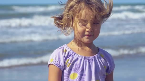 Joyeux belle petite fille en face de l'océan sauvage souriant lent gros plan
 - Séquence, vidéo