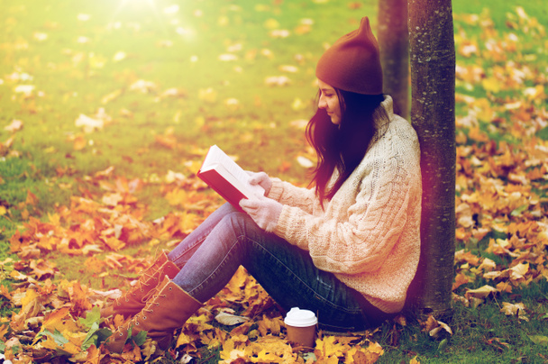 woman with book drinking coffee in autumn park - Fotó, kép