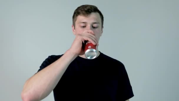 Młody człowiek sody pitnej. Młody mężczyzna w czarnej koszuli picia sody, na białym tle - Materiał filmowy, wideo