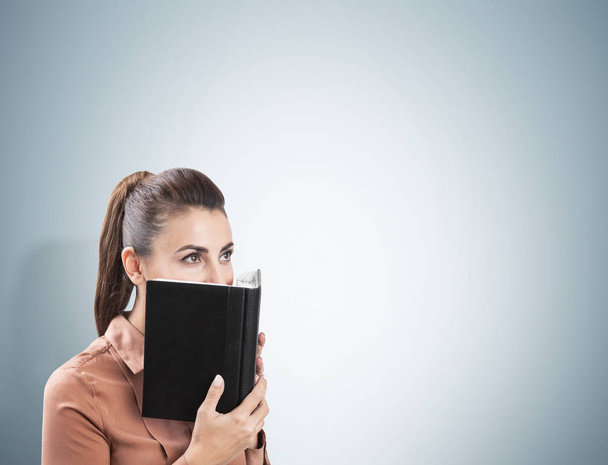 Businesswoman covering face with planner, gray - Foto, imagen
