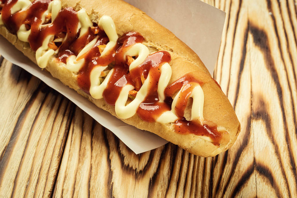 Hot Dog alla griglia con salsa, Hot Dog con senape gialla, cipolla, sottaceti e patatine fritte, gustosi hot-dog con verdure su fondo di legno, da vicino, hot dog con senape, ketchup e gusto
  - Foto, immagini