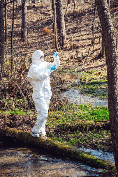 female scientist examining the liquid contents of a  test tube in the forest. Ecology and environmental pollution concept. - Fotografie, Obrázek