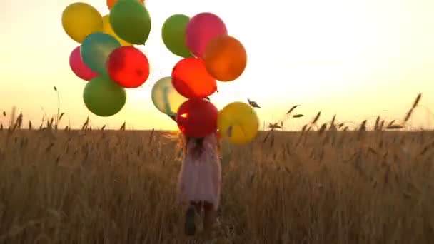 giovane ragazza in abito con palloncini colorati sta correndo attraverso il campo
. - Filmati, video