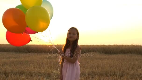 girl walking in a field with balloons - Filmati, video