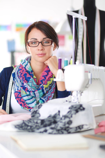 Young woman sewing while sitting at her working place . - Foto, afbeelding