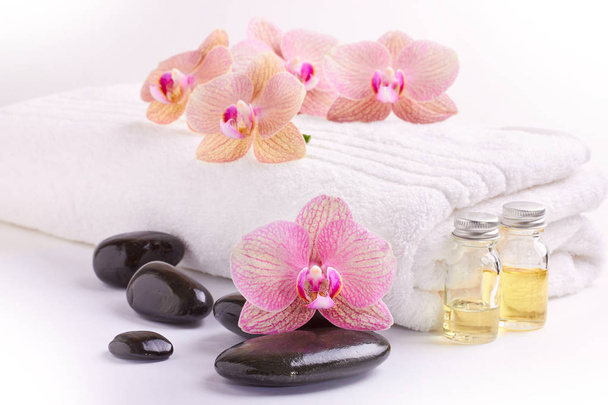Pink orchids, moisturizing oils and spa stones on white - Valokuva, kuva