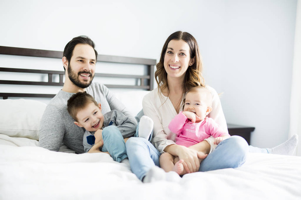 four peoples family on a white bed. - Фото, изображение