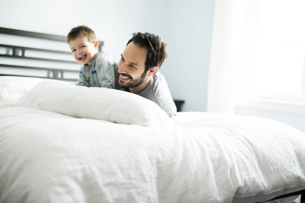 Father and son in bed, happy time on bed - Фото, изображение