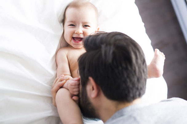 happy father playing with adorable baby in bedroom - Foto, Imagem