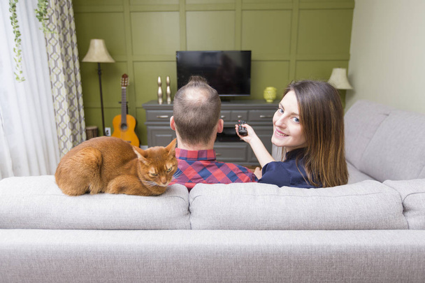 Beautiful couple watching TV sitting on couch at home - Valokuva, kuva
