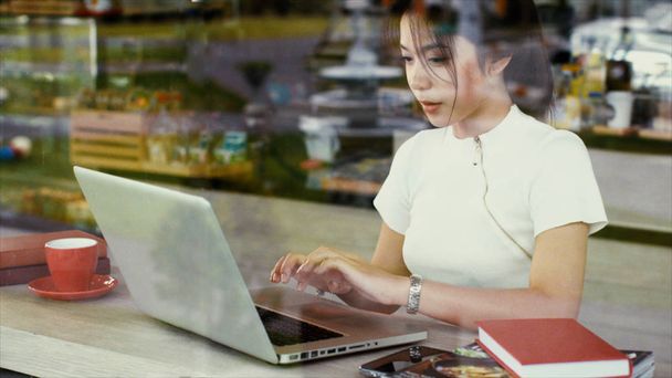 Mooie Aziatische tienermeisje is chatten op een laptop - Foto, afbeelding