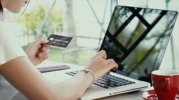 若いアジアの女の子使用クレジット カードはノート パソコンのオンライン ショッピング - 写真・画像