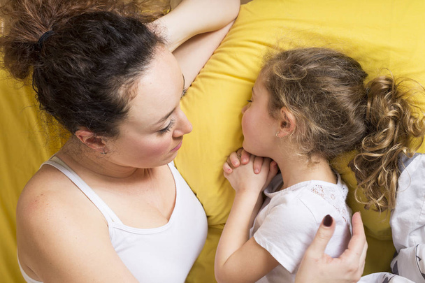 Mother and daughter at home in the bed. - Foto, Bild