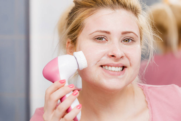 Happy woman using facial cleansing brush - Foto, afbeelding
