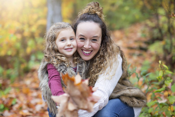 Young mother playing with her daughter in autumn park - Foto, Bild