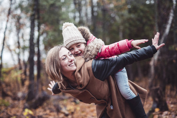 Portrait of a smiling young woman with a little girl in autumn - Photo, image