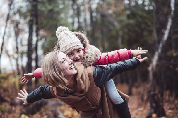 Portrait of a smiling young woman with a little girl in autumn - Photo, Image