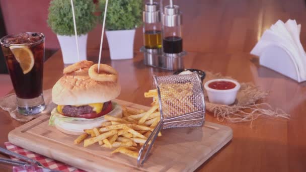 Burger au fromage américain avec fromage, bœuf, tomate, laitue, rondelles d'oignon avec bâtonnets, frites et soda boisson froide avec tranche de citron. Plan panoramique
. - Séquence, vidéo
