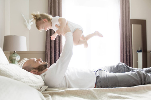 Father with adorable baby toddler on bed - Foto, imagen