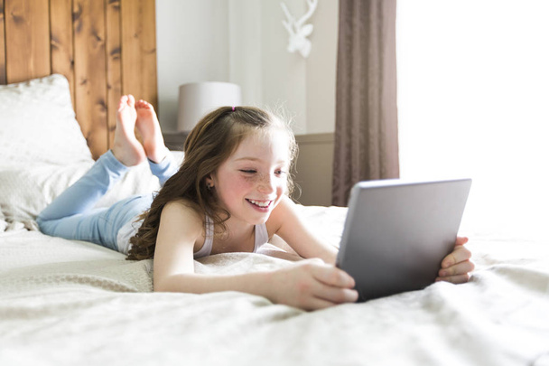 girl lay bed at home with tablet technology - 写真・画像
