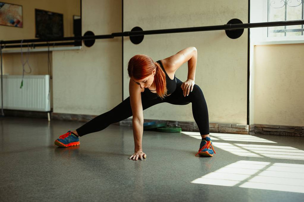 woman stretching her legs in gym - Фото, изображение
