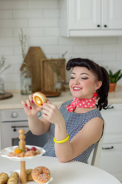 pin up girl emotionally eating a donut and laughing in the kitchen at the table - Photo, Image