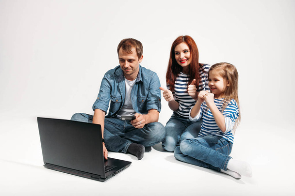 Happy family Father, mother and child lying on the floor with laptop credit card on white background isolated - Foto, afbeelding