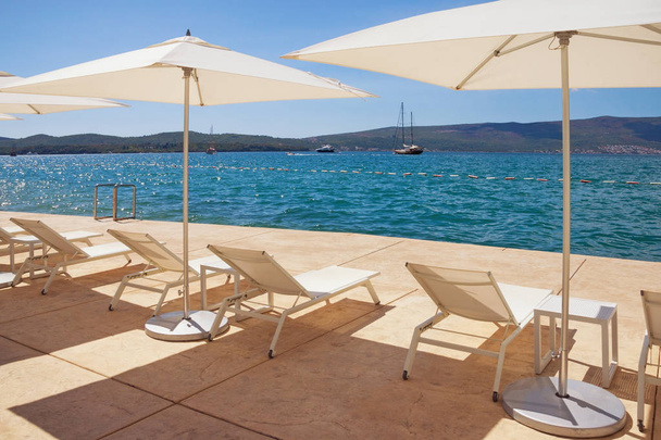 Sonnenschirme und Liegestühle am Strand. Kotor Bucht der Adria, Montenegro - Foto, Bild