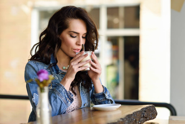 Femme assise à l'intérieur dans un café urbain portant des vêtements décontractés
 - Photo, image