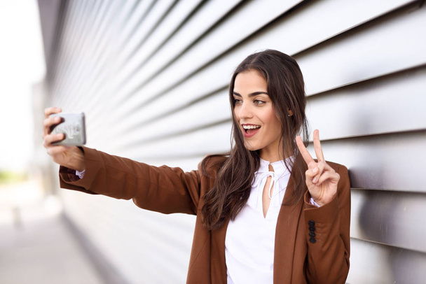 V sig を行うスマート フォンで selfie 写真を撮る若い女性 - 写真・画像