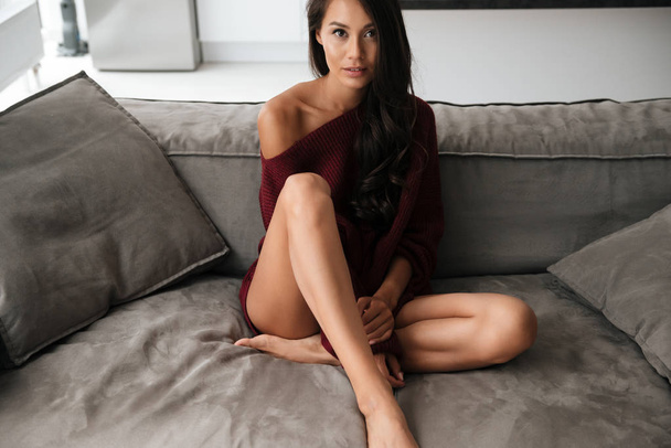 Beautiful asian woman with long hair sitting on a couch - Foto, afbeelding