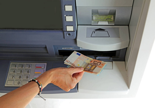 το χέρι της νεαρής γυναίκας ενώ απόσυρση τραπεζογραμματίων 50 ευρώ από μια - Φωτογραφία, εικόνα