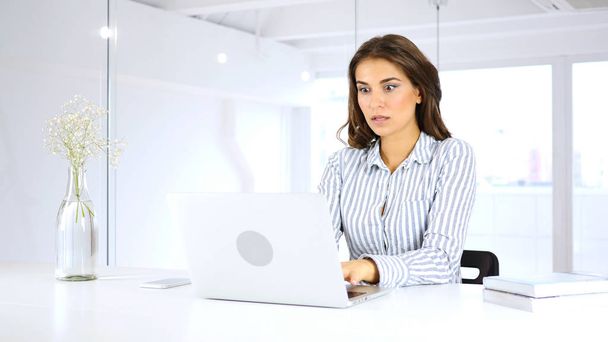Schockierte junge Frau arbeitet im Büro an Laptop - Foto, Bild