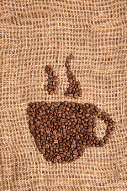 Tasse Kaffee, Kaffeekörner auf texturiertem braunem Hintergrund - Foto, Bild