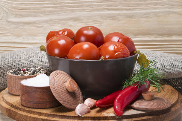 canned tomato in a plate with spices on a wooden background - Foto, Imagem