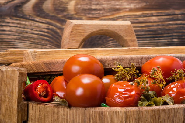 tomatoes and condiments in a barrel under the lid, a wooden background close-up - Foto, Imagem