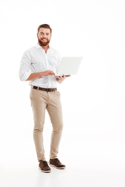 Happy young bearded man using laptop. - Fotoğraf, Görsel