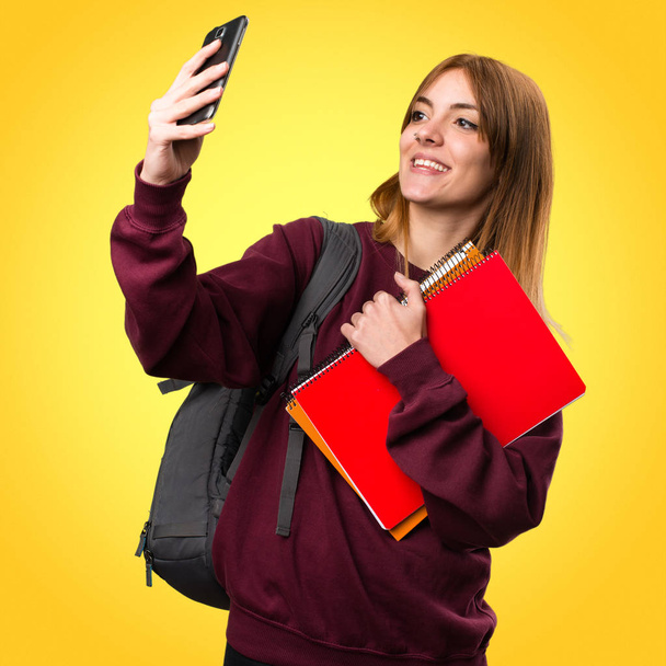 Student woman talking to mobile on colorful background - 写真・画像